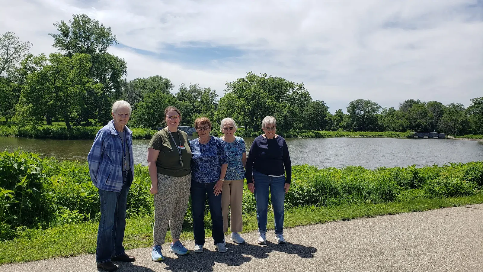 Cascade Creek Memory Care residents posing for a photo outside in front of a pond