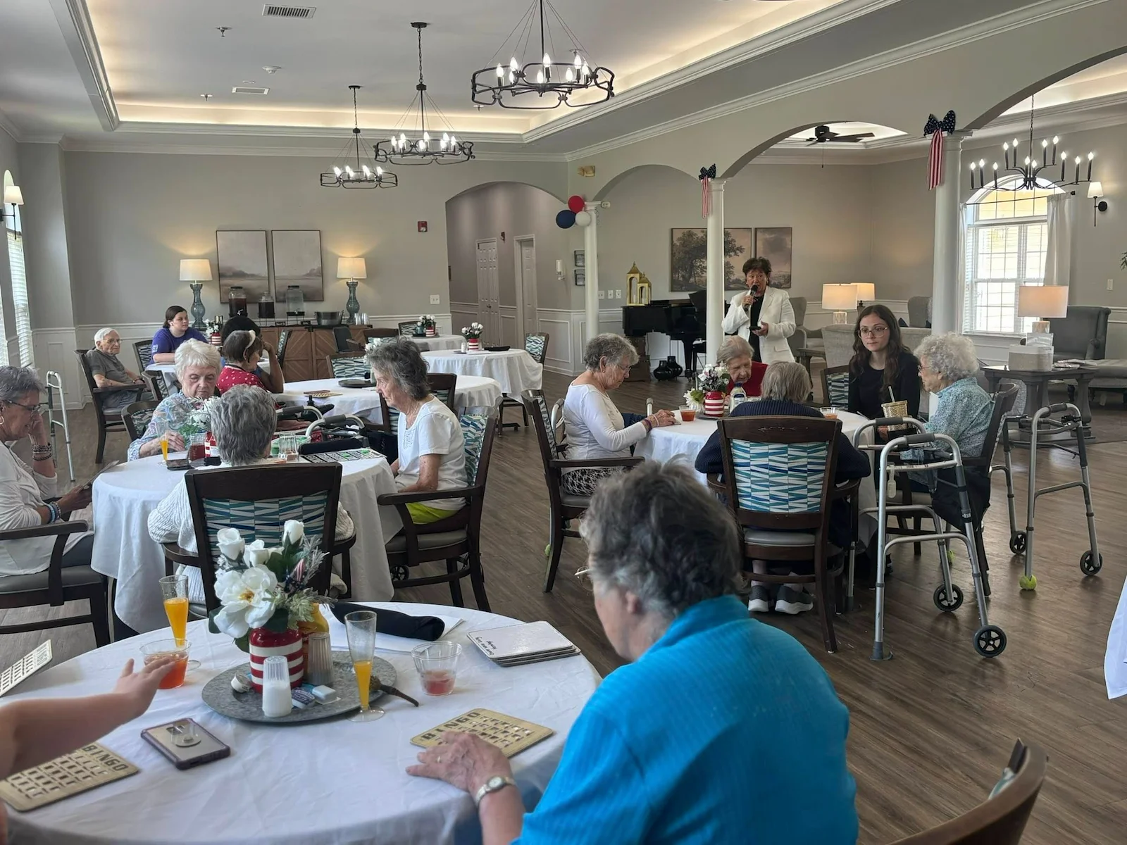 Seniors at Charter Senior Living of Hermitage in Hermitage, TN, playing Bingo together and enjoying refreshing drinks in a well-lit common area, promoting social engagement in independent living, assisted living, and memory care.