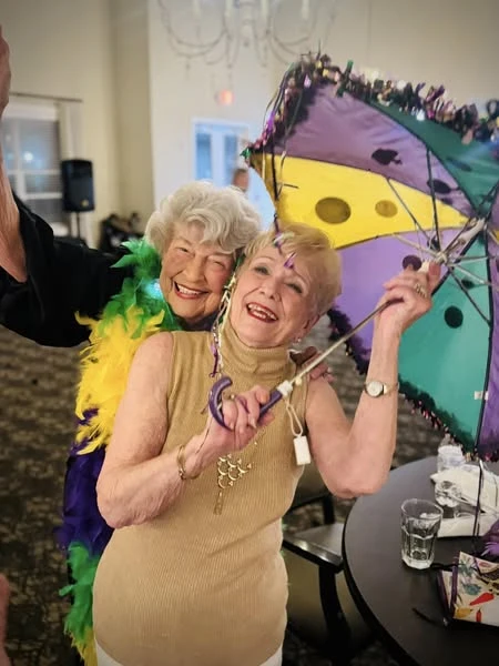 Two ladies enjoying the Mardi Gras party at The Vincent Senior Living