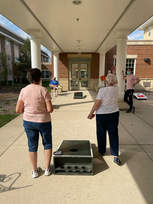 Covenant Living at The Holmstad in Batavia, IL, residents enjoying an outdoor activity with good community - cornhole