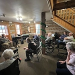 Seniors in assisted living and memory care at Charter Senior Living of Hasmer Lake in Jackson, WI, gathered in a cozy, comfortable room enjoying a music session together.