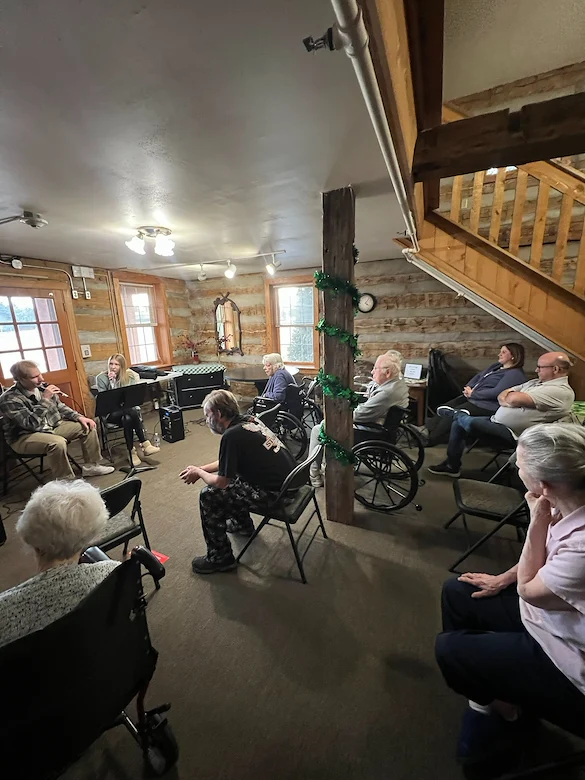Seniors in assisted living and memory care at Charter Senior Living of Hasmer Lake in Jackson, WI, gathered in a cozy, comfortable room enjoying a music session together.