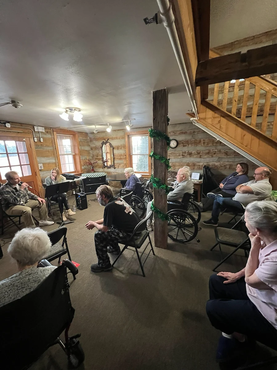 Seniors in assisted living and memory care at Charter Senior Living of Hasmer Lake in Jackson, WI, gathered in a cozy, comfortable room enjoying a music session together.