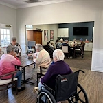 Two groups of seniors at Charter Senior Living of Hermitage in Hermitage, TN, gathered in a common area, with one group working on a puzzle and another socializing, fostering community and engagement in independent living, assisted living, and memory care.