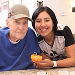Chelsea Place Memory Care staff member holding a mini pumpkin