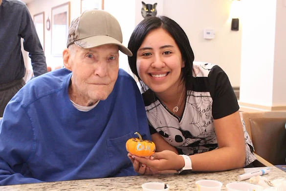 Chelsea Place Memory Care staff member holding a mini pumpkin