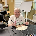 Whealdon Estates by Barclay House senior living community offering independent living in Baton Rouge, LA, resident making spring door crafts to celebrate the start of spring