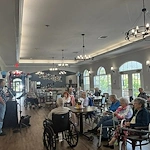 Seniors at Charter Senior Living of Hermitage in Hermitage, TN, gathered together listening to a live musician singing, enjoying engaging entertainment in independent living, assisted living, and memory care.