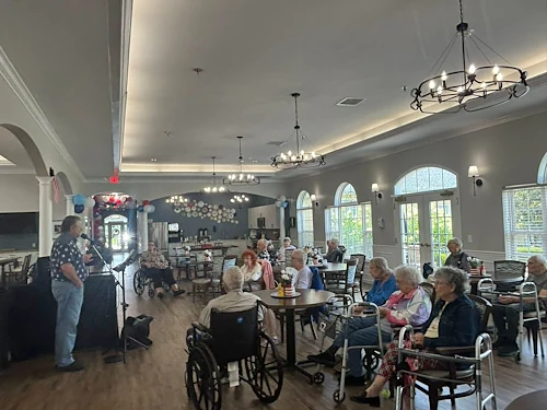 Seniors at Charter Senior Living of Hermitage in Hermitage, TN, gathered together listening to a live musician singing, enjoying engaging entertainment in independent living, assisted living, and memory care.