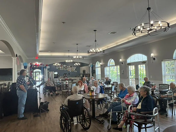 Seniors at Charter Senior Living of Hermitage in Hermitage, TN, gathered together listening to a live musician singing, enjoying engaging entertainment in independent living, assisted living, and memory care.