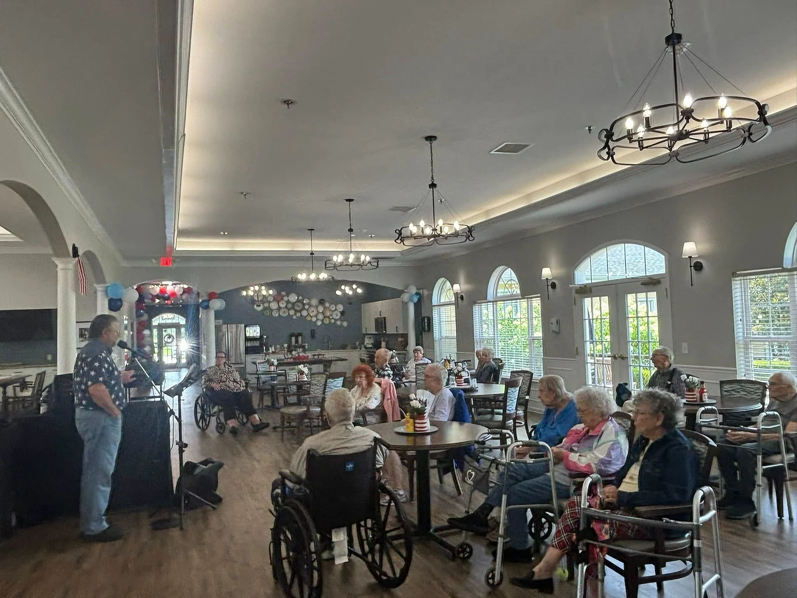 Seniors at Charter Senior Living of Hermitage in Hermitage, TN, gathered together listening to a live musician singing, enjoying engaging entertainment in independent living, assisted living, and memory care.