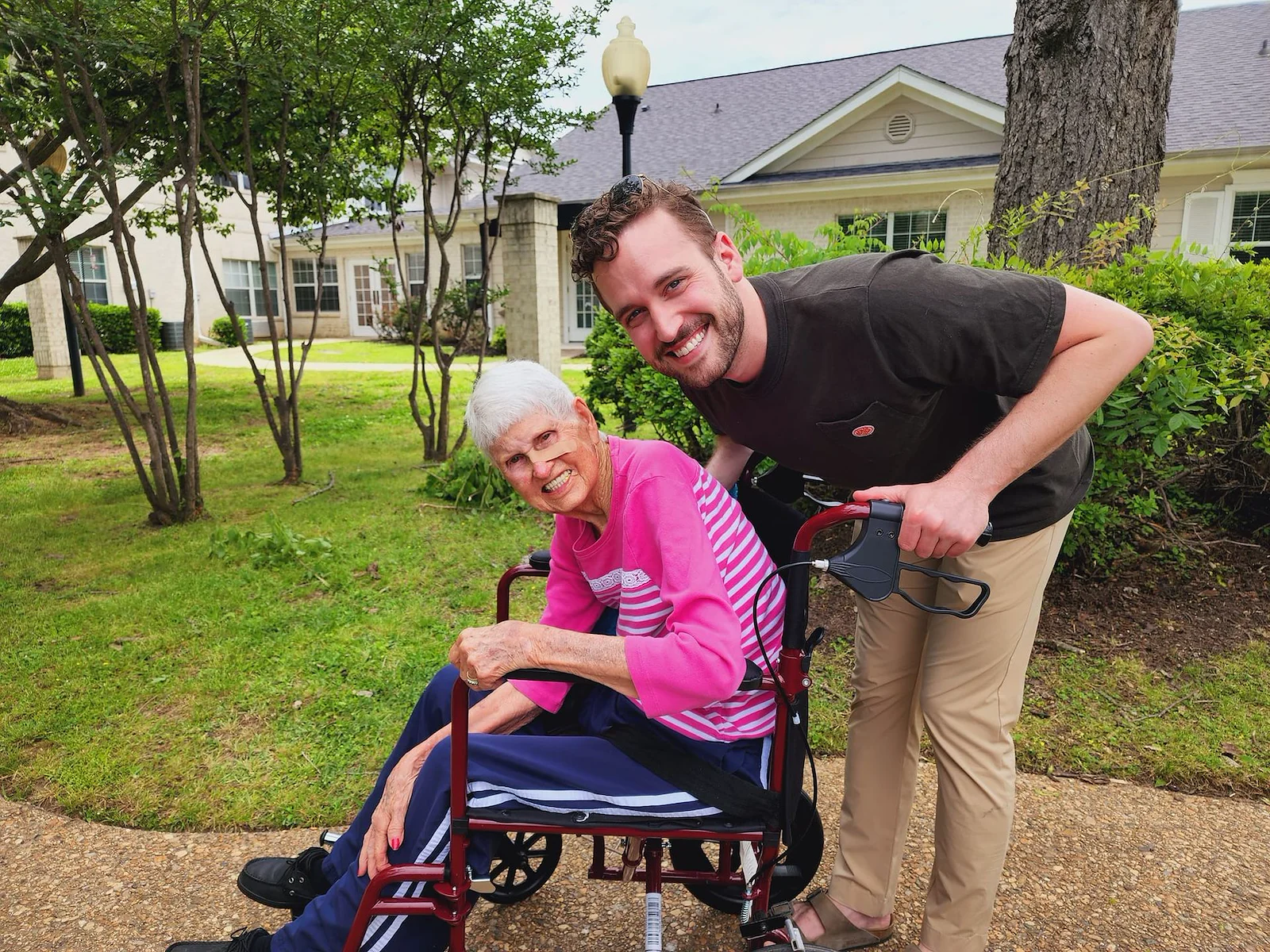 The Chateaus at Montclair Senior Memory Care in Shreveport, LA resident in a wheelchair being pushed by a staff member