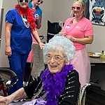 Kidron Bethel Village senior living community and continuing care retirement community (CCRC) offering independent living, assisted living, and respite care in North Newton, KS, smiling resident wearing a boa at a celebration