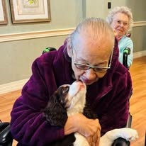 senior cuddling a puppy at Serenades at Longwood