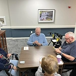 Seniors at Charter Senior Living of Jackson in Jackson, TN, gathered around a table playing cards and engaging their minds in a bright, comfortable room, promoting social interaction in assisted living and memory care.