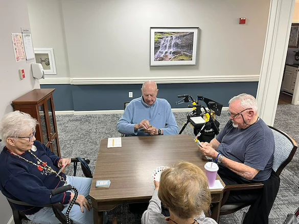 Seniors at Charter Senior Living of Jackson in Jackson, TN, gathered around a table playing cards and engaging their minds in a bright, comfortable room, promoting social interaction in assisted living and memory care.