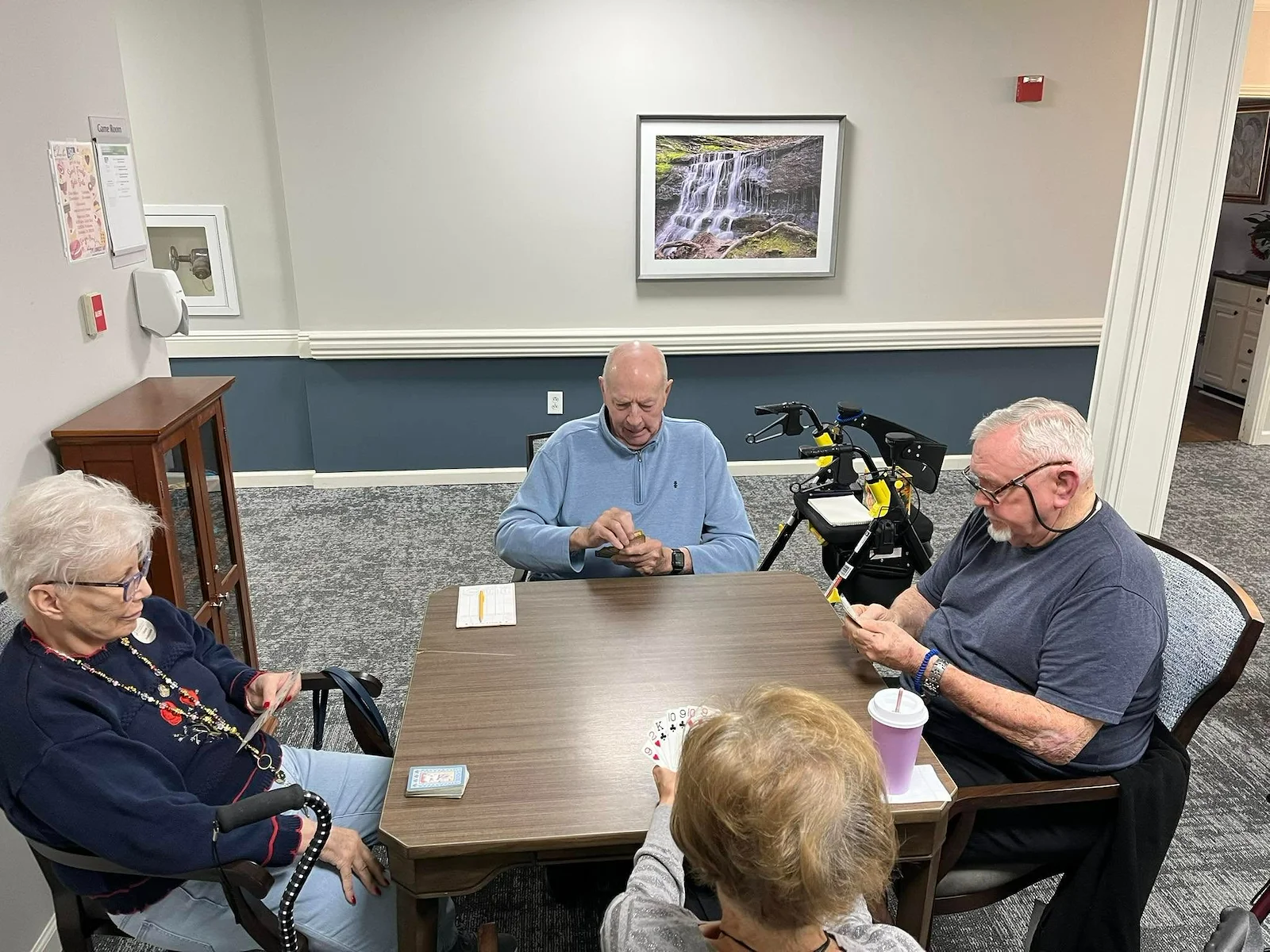 Seniors at Charter Senior Living of Jackson in Jackson, TN, gathered around a table playing cards and engaging their minds in a bright, comfortable room, promoting social interaction in assisted living and memory care.