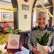 The Oaks of Pasadena resident smiling with a plant