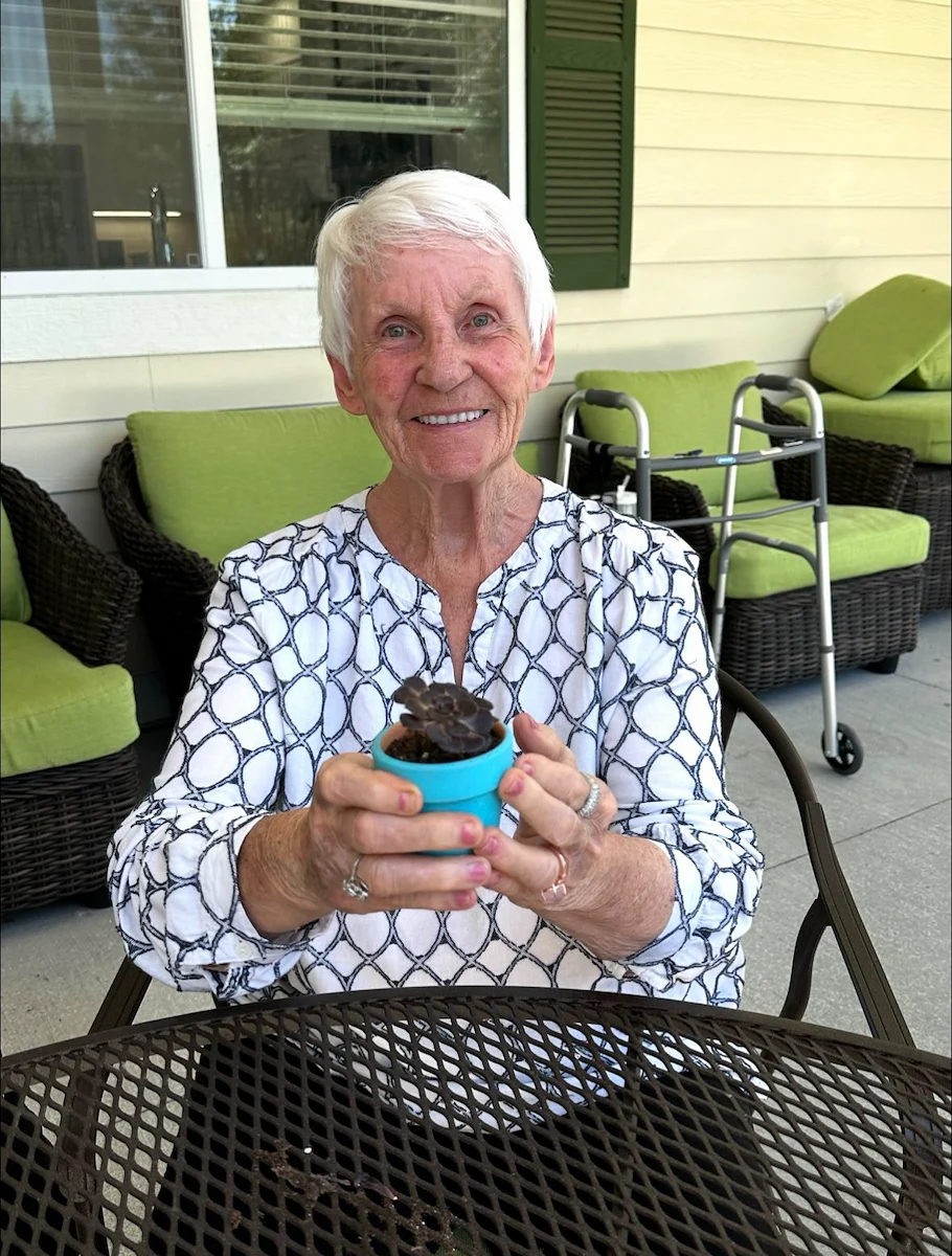 Faith Cottages Memory Care Basehor, KS, happy resident with plant from a community activity