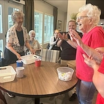 Excited resident and others participating in a fun group activity with ping pong balls and baskets at Charter Senior Living of Hopkinsville in Hopkinsville, KY, fostering joy and social engagement in assisted living and memory care.