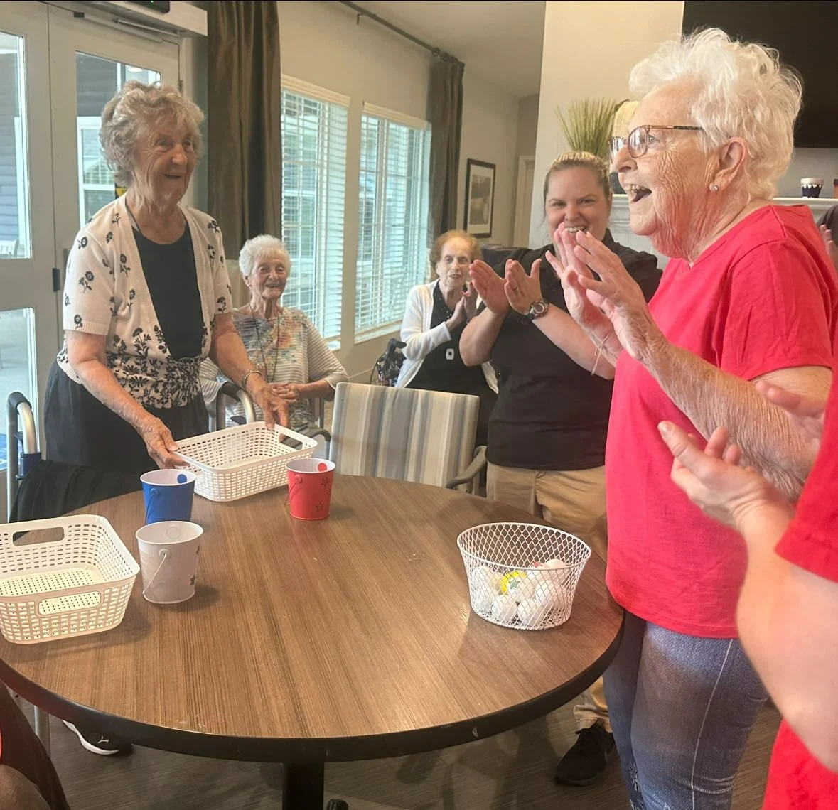 Excited resident and others participating in a fun group activity with ping pong balls and baskets at Charter Senior Living of Hopkinsville in Hopkinsville, KY, fostering joy and social engagement in assisted living and memory care.