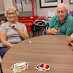 Seniors at Charter Senior Living of Hopkinsville in Hopkinsville, KY, sitting around a table playing UNO and smiling, promoting mental engagement and social interaction in assisted living and memory care.