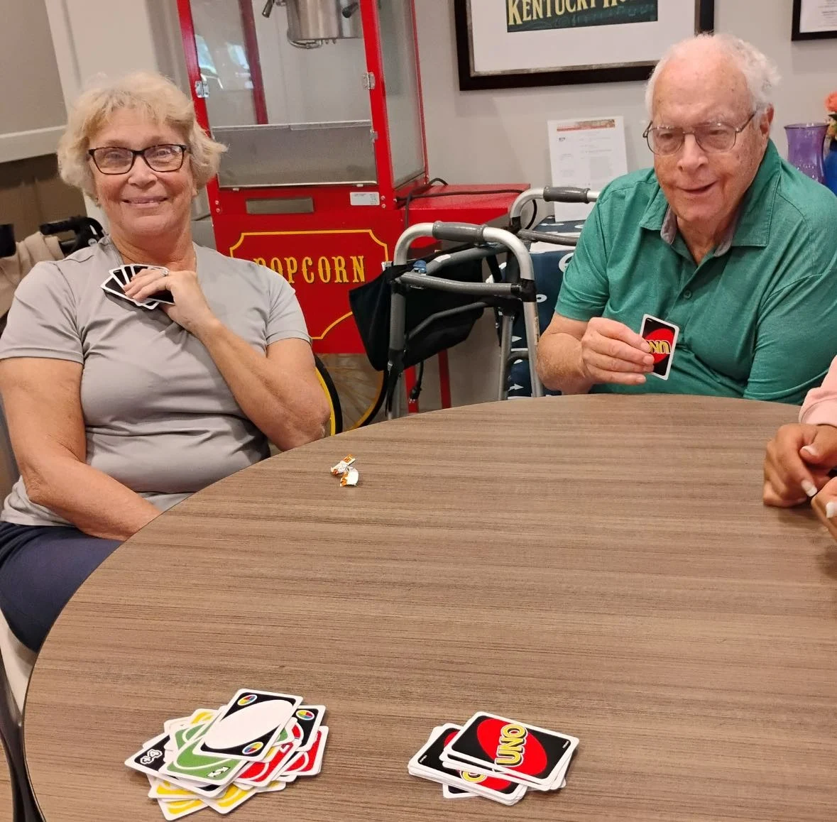 Seniors at Charter Senior Living of Hopkinsville in Hopkinsville, KY, sitting around a table playing UNO and smiling, promoting mental engagement and social interaction in assisted living and memory care.