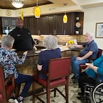 Maple Ridge Gracious Retirement Living Hawthorn Senior Independent Living in Cedar Park, Texas residents socializing with a staff member in the kitchen