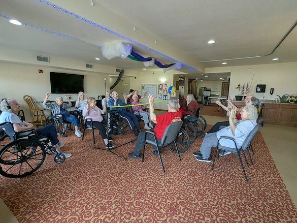 Seniors in assisted living and memory care at Charter Senior Living of Hasmer Lake in Jackson, WI, playing indoor balloon volleyball, promoting active lifestyles and social engagement.