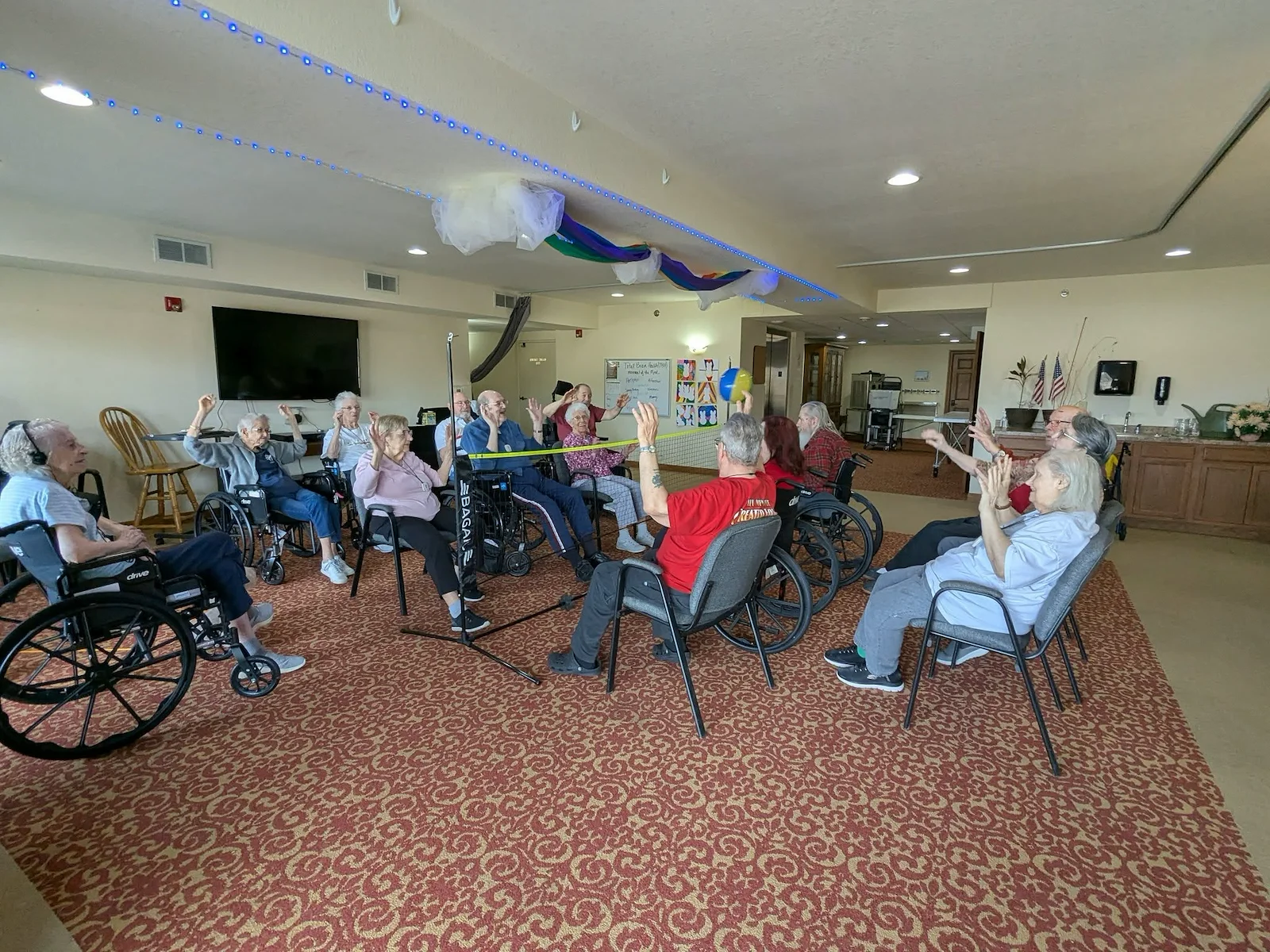 Seniors in assisted living and memory care at Charter Senior Living of Hasmer Lake in Jackson, WI, playing indoor balloon volleyball, promoting active lifestyles and social engagement.