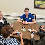 Cascade Creek Memory Care residents playing a card game with a staff member