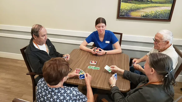 Cascade Creek Memory Care residents playing a card game with a staff member