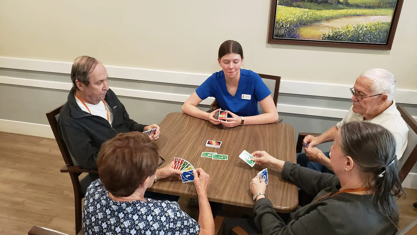 Cascade Creek Memory Care residents playing a card game with a staff member