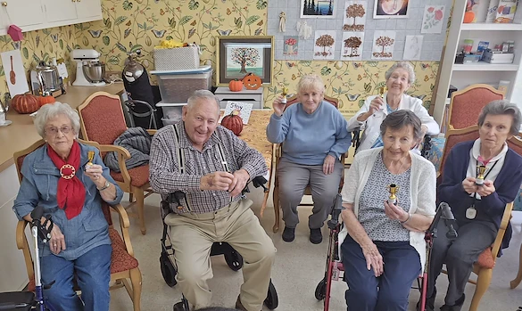 Wesley Manor Assisted Living Community offering assisted living and continuing care retirement community (CCRC) services in Louisville, KY, smiling residents spending time together and holding up tiny trophies