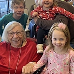 American House Stone senior living community offering independent living and respite care in Rochester Hills, MI, smiling resident enjoying a visit from little kids