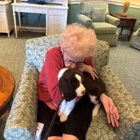 senior cuddling a puppy at Serenades at Longwood