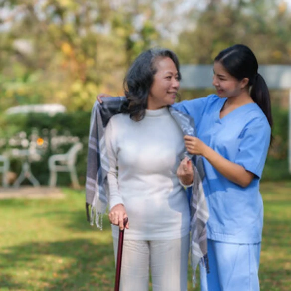 a caring nurse walking with an elderly woman with a cane