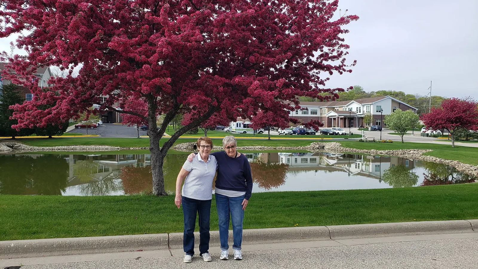 Cascade Creek Memory Care residents hugging in front of a pond for a photo