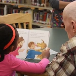 Grace Point Place Assisted Senior Living Memory Care in Oak Lawn, IL resident being read a book by a child