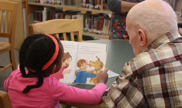 Grace Point Place Assisted Senior Living Memory Care in Oak Lawn, IL resident being read a book by a child