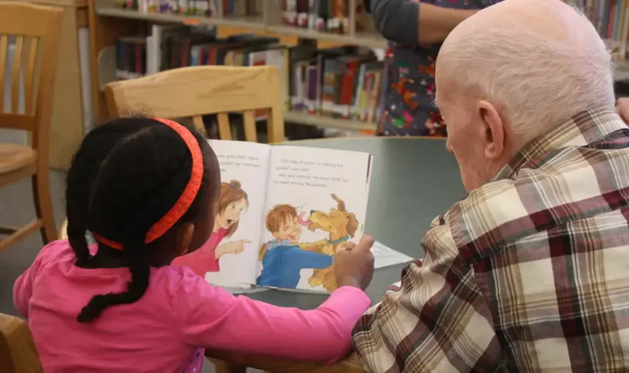 Grace Point Place Assisted Senior Living Memory Care in Oak Lawn, IL resident being read a book by a child