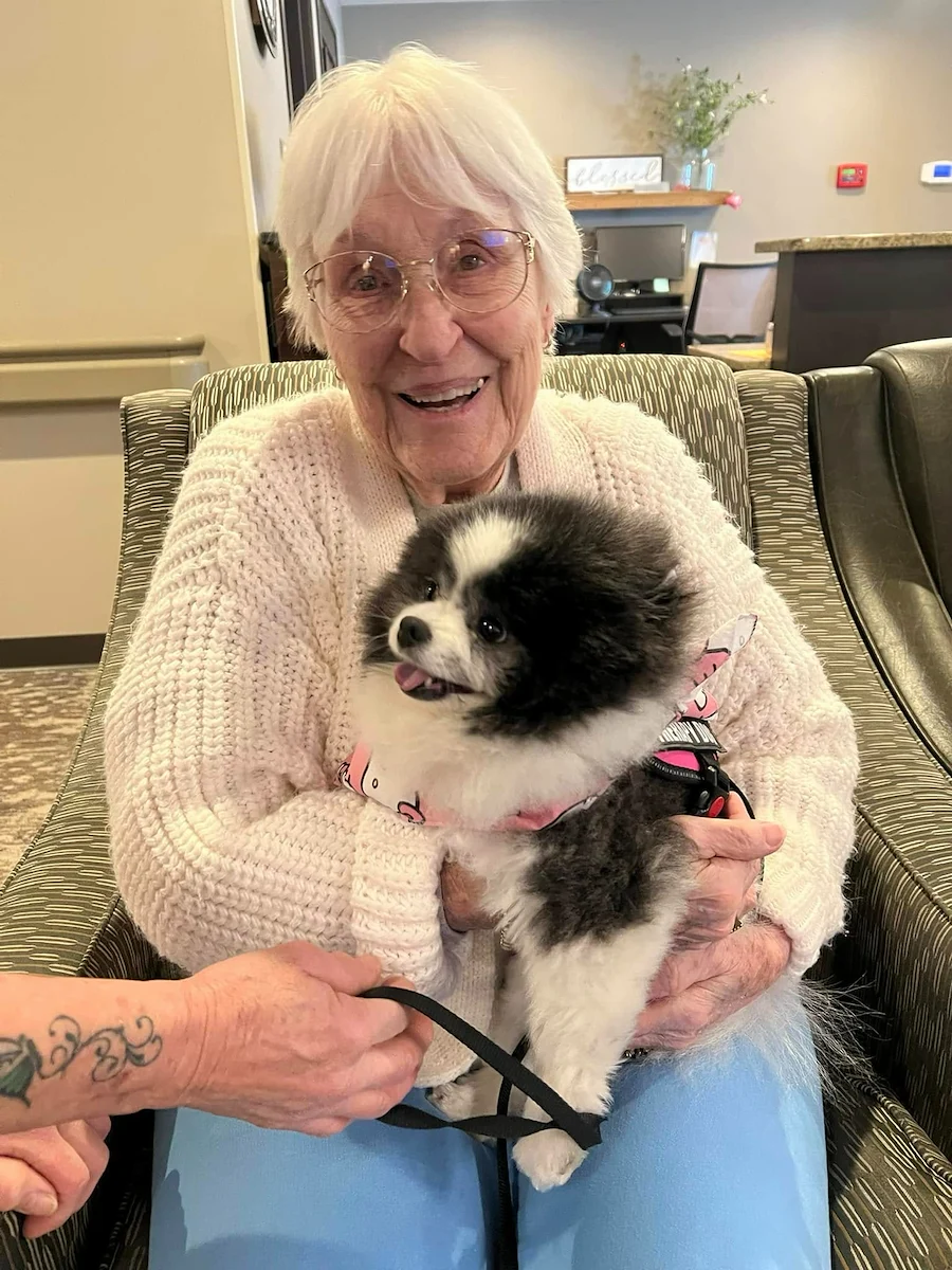 Park Vista Retirement Living - Camanche, IA, resident smiles with a visiting dog