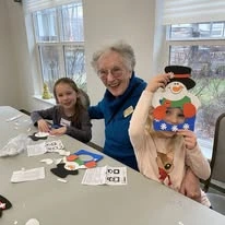 The Highlands Gracious Retirement Living Hawthorn Senior Independent Living in Westborough, Massachusetts resident making a snowman craft with kids