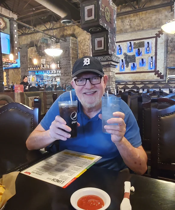 American House Westland Venoy senior living community offering independent living, assisted living, and respite care in Westland, MI, resident holding two beverages at an outing to a restaurant