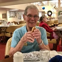 Meadowlark Estates Gracious Retirement Living Hawthorn Senior Independent Living in Lawrence, Kansas resident eating a hot dog in the dining room