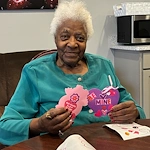 American House Elmwood, senior living community offering independent living, assisted living, memory care, and respite care in Rochester Hills, MI, smiling resident doing Valentine's Day arts and crafts