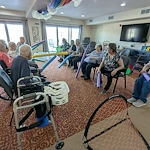 Seniors in assisted living and memory care at Charter Senior Living of Hasmer Lake in Jackson, WI, playing an indoor game with pool noodles and nets, encouraging physical activity and social fun