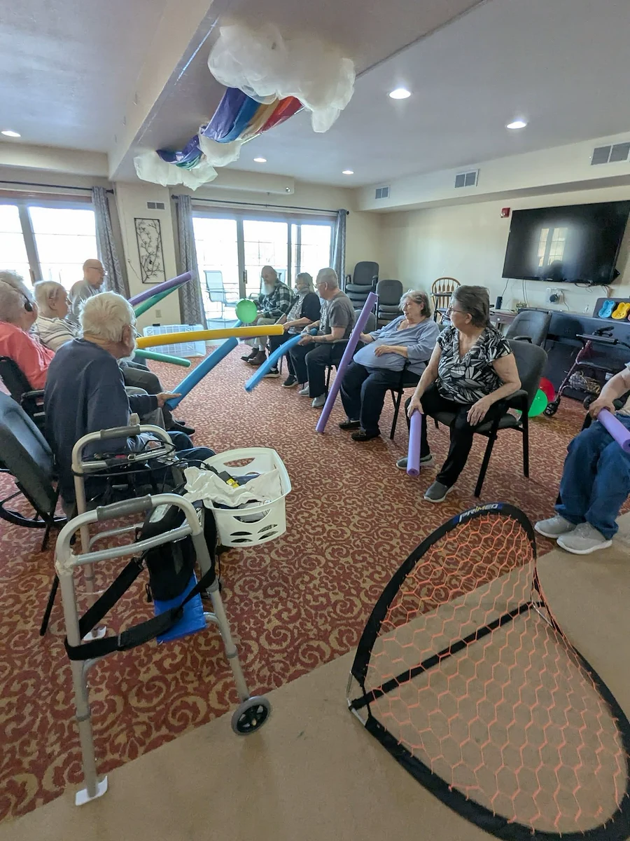 Seniors in assisted living and memory care at Charter Senior Living of Hasmer Lake in Jackson, WI, playing an indoor game with pool noodles and nets, encouraging physical activity and social fun