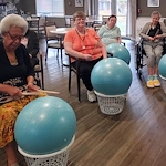 American House Westland Venoy senior living community offering independent living, assisted living, and respite care in Westland, MI, residents drumming on an exercise ball