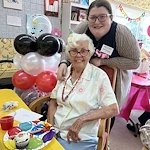 Wesley Manor Assisted Living Community offering assisted living and continuing care retirement community (CCRC) services in Louisville, KY, resident enjoying a birthday celebration with a staff member nearby